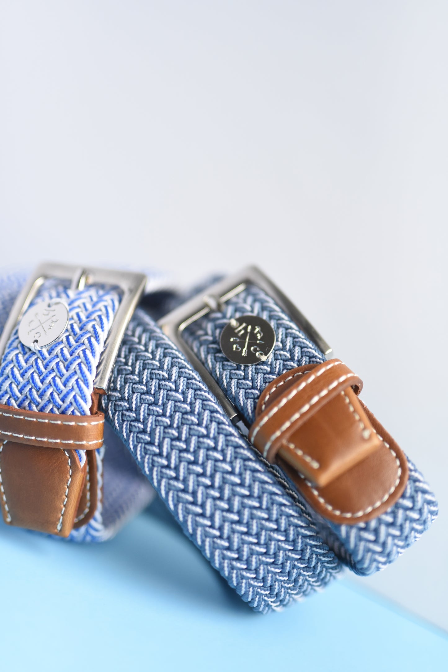 Blue woven belt with brown leather ends on a light blue background